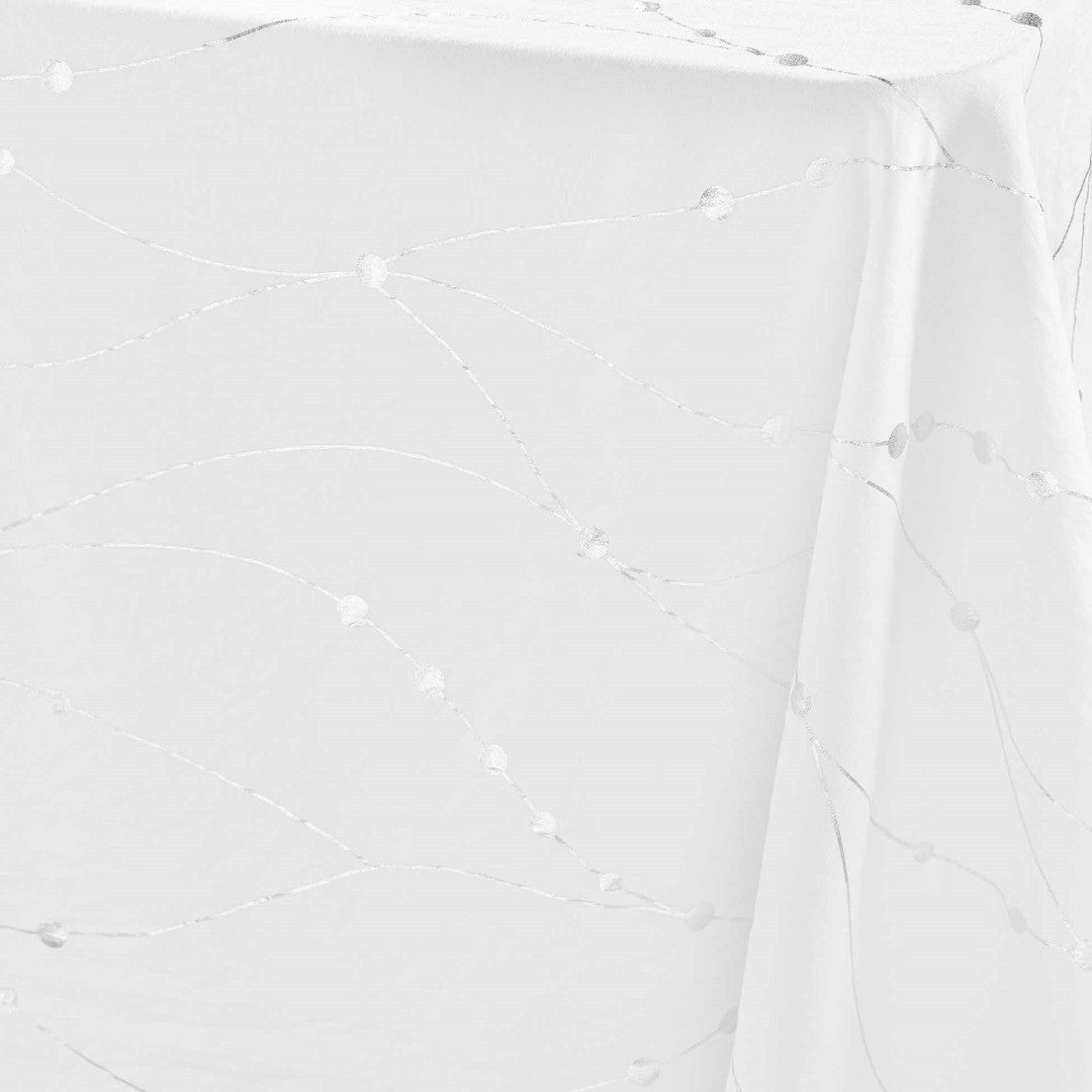 Nærbillede af hjørnet på Firmament Metallic hvid dug med sølvstjerner